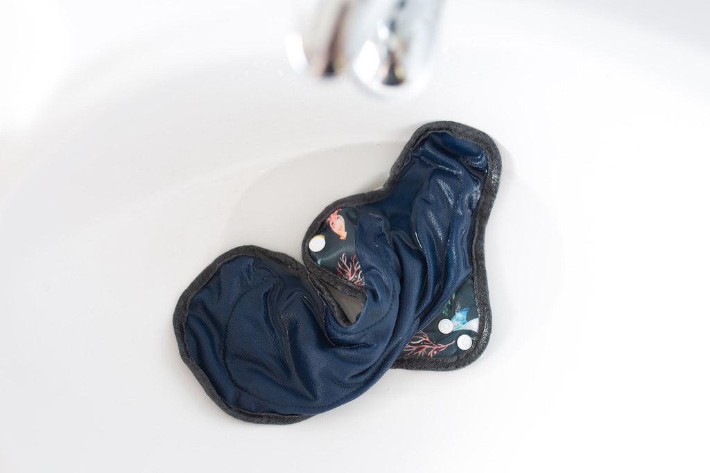A cloth pad rests in a sink of cold running water for a pre rinse 