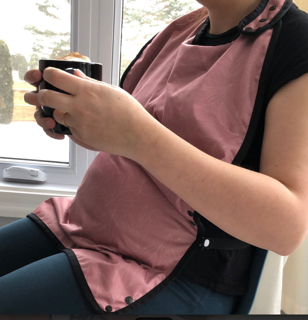 Lady wearing reusable smock, sitting down, drinking coffee