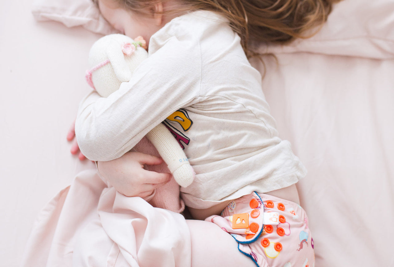 toddler wearing potty training pants and hugging stuffed animal