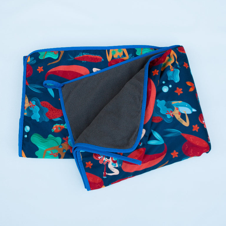 Colorful mermaid-themed fabric with sea creatures and ocean motifs on a blue background.