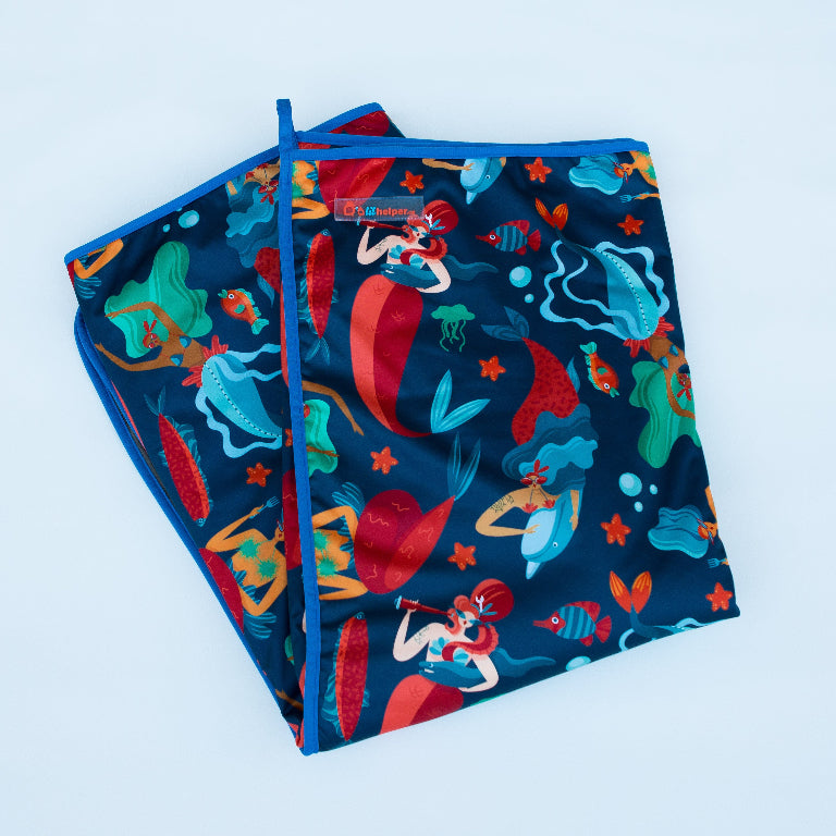 Colorful mermaid-themed blanket with fish and sea creatures against a blue background.