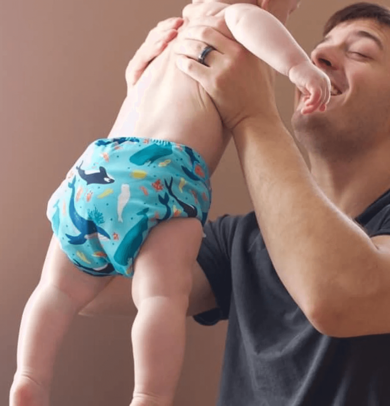 a dad holding a baby up in a cloth diaper