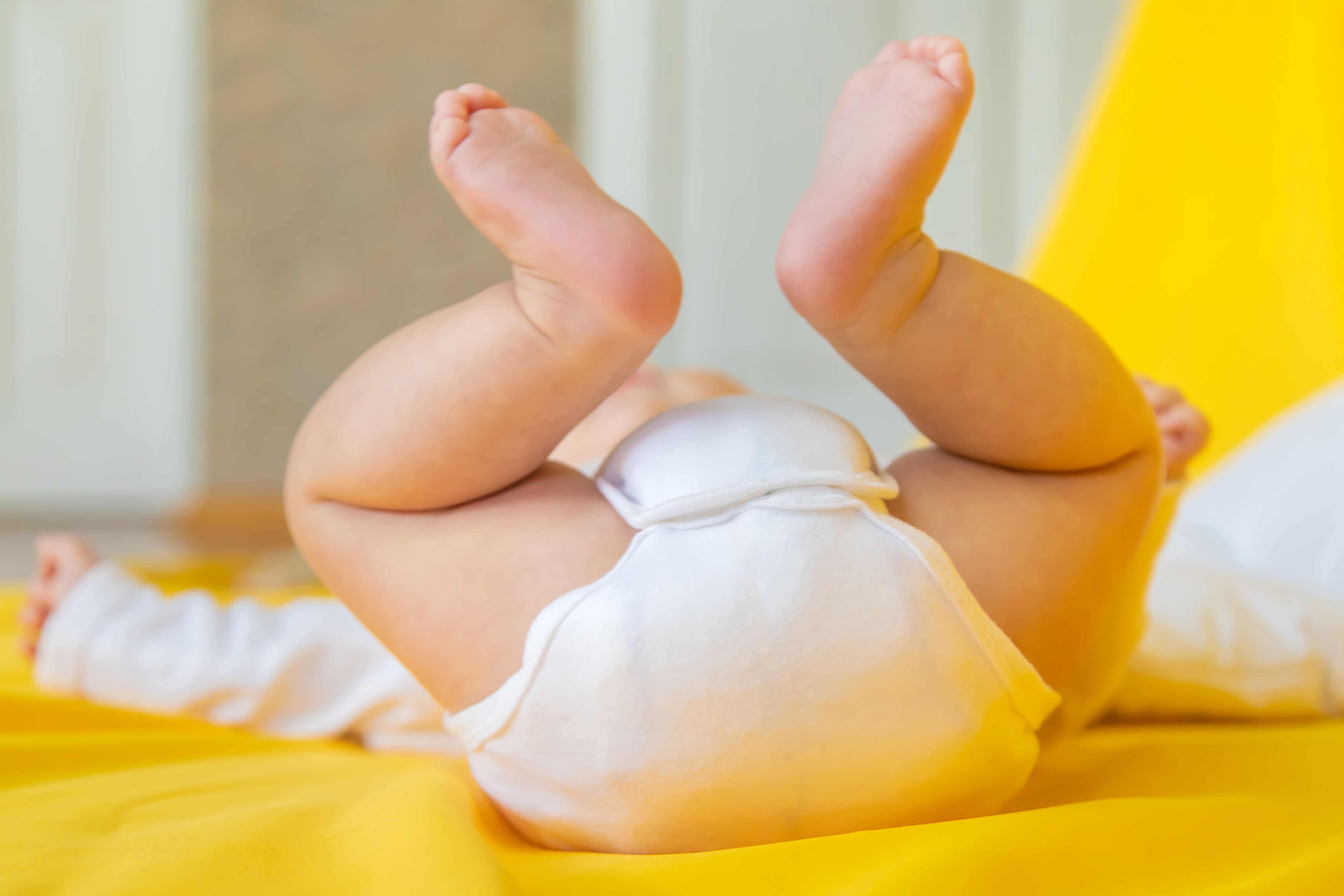 A baby laying on the floor, wearing a cloth diaper with inserts